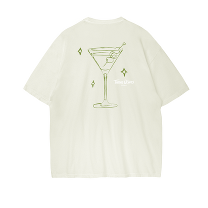 Beige t-shirt with a martini glass graphic  and Three Olives vodka logo on a white background